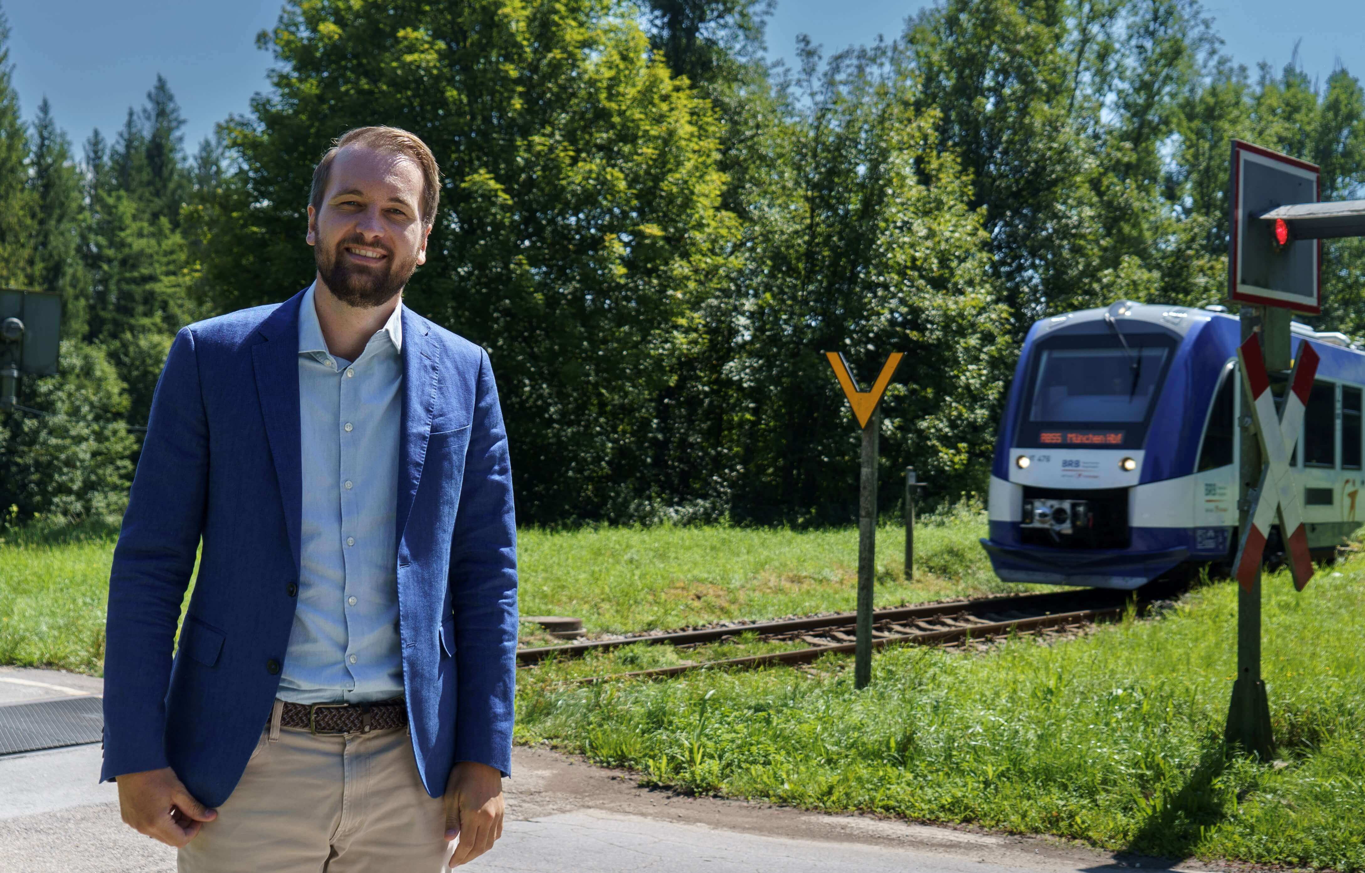 Projektleiter Arthur Zeller an einem unbeschrankten Bahnübergang, im Hintergrund fährt ein Zug.
